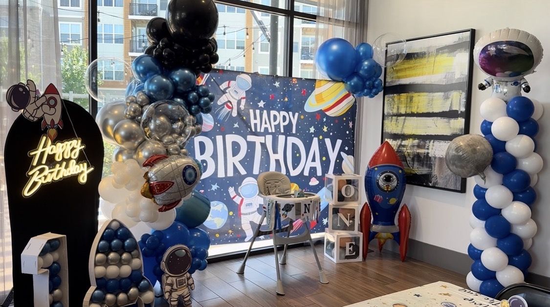 Full space first birthday setup with backdrop, rocket and high chair