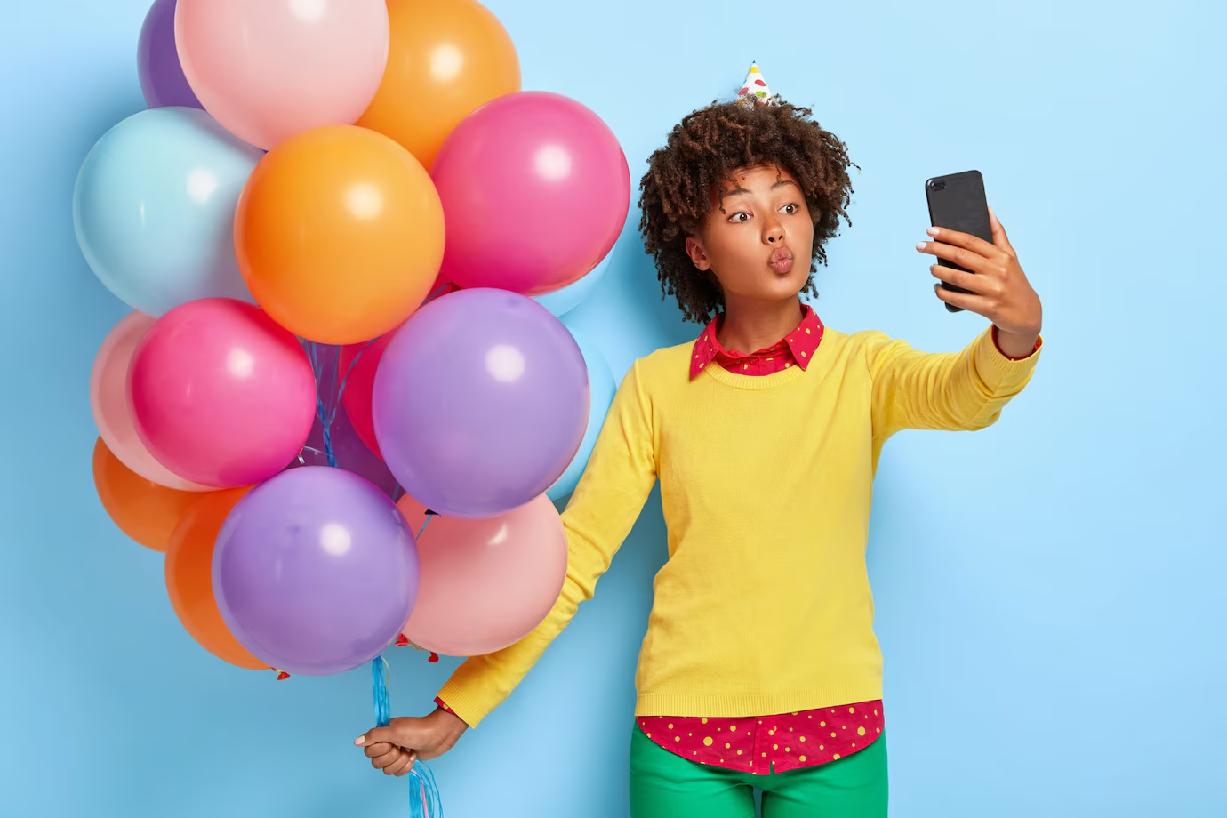 pretty-young-woman-holds-multicolored-balloons-while-posing-yellow-sweater_273609-31812
